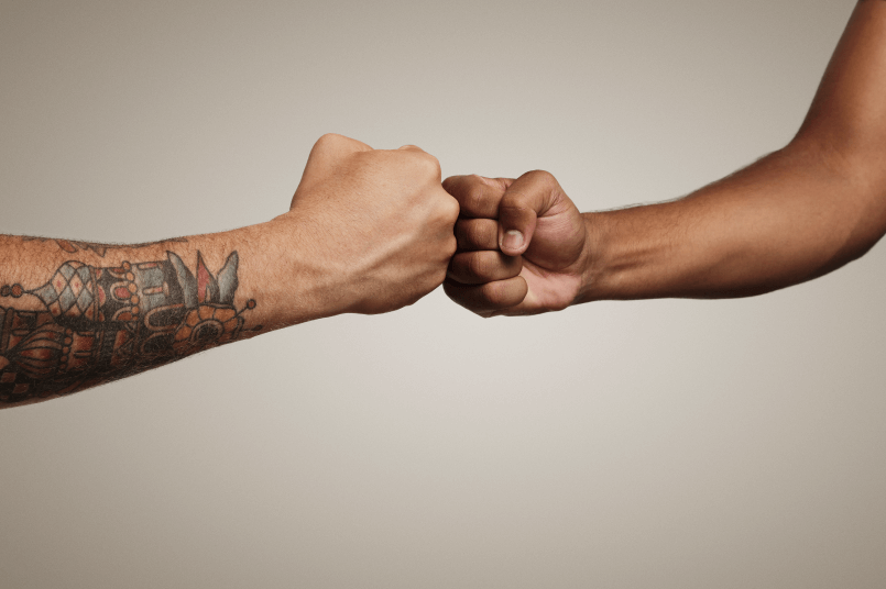 Two friends with tattoos bumping fists.
